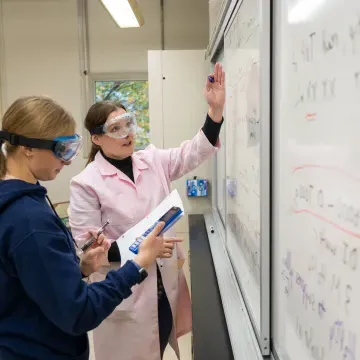 chemistry lab students and faculty at white board 